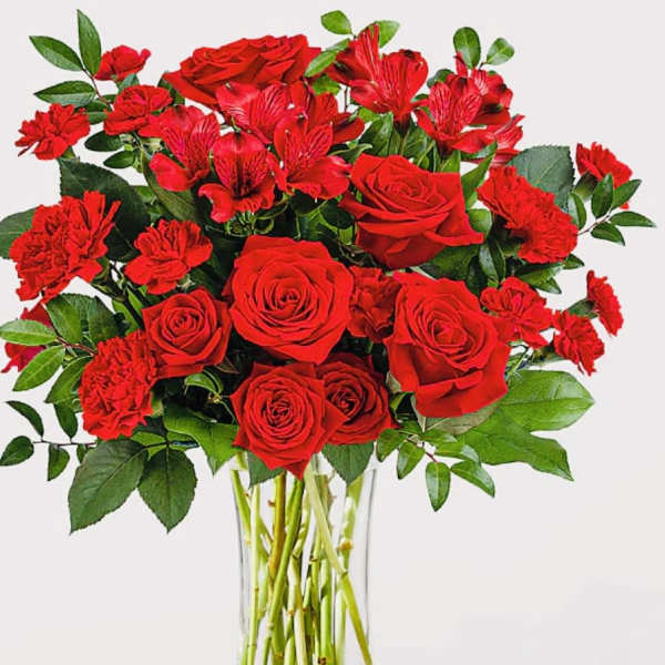 Red roses and carnations in a clear glass vase