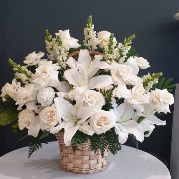 White lilies and roses arranged in a wicker basket