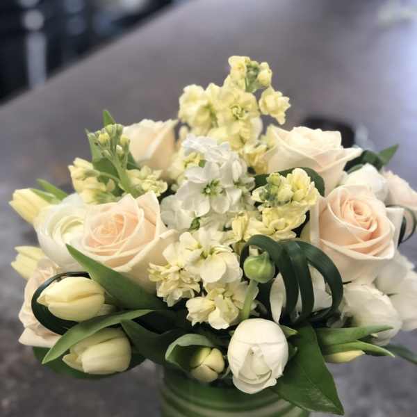 Cream roses and white tulips in a striped glass vase