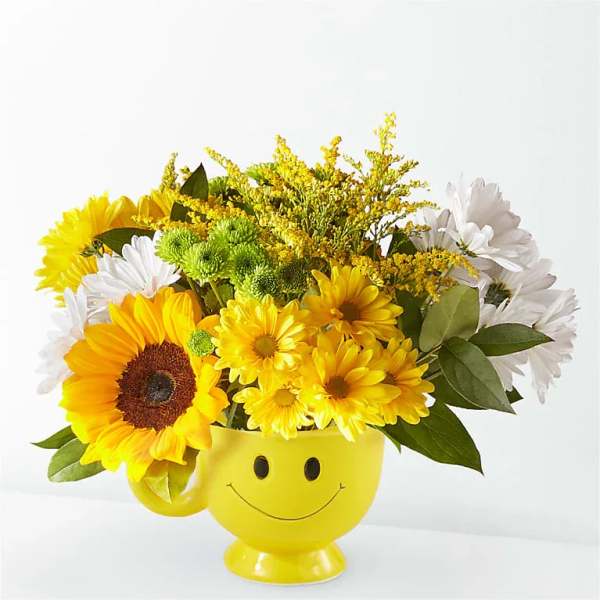 Yellow smiley-face mug filled with sunflowers and daisies