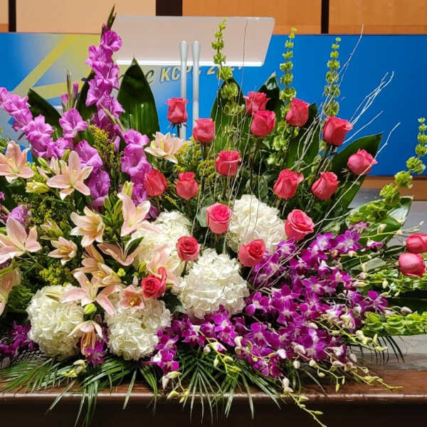 Large altar-style arrangement with pink roses, lilies, orchids and white hydrangeas