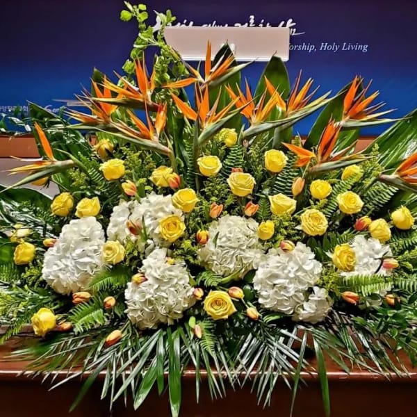 Large yellow and white floral stage arrangement with birds of paradise and tropical foliage