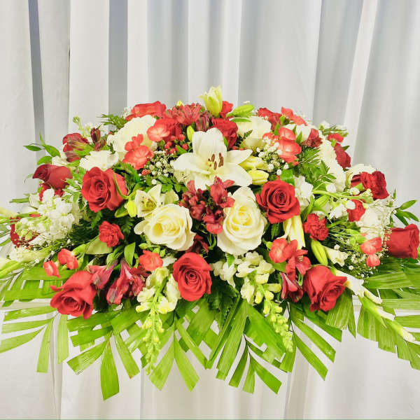 Large red and white floral arrangement with palm fronds