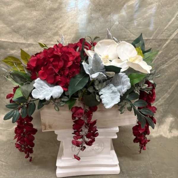 Red and white floral arrangement in a white pedestal container