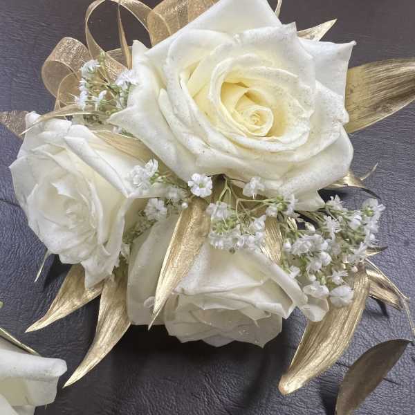 White roses with small white filler flowers and gold ribbon accents