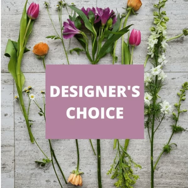Assorted flowers and stems arranged around a "Designer’s Choice" sign