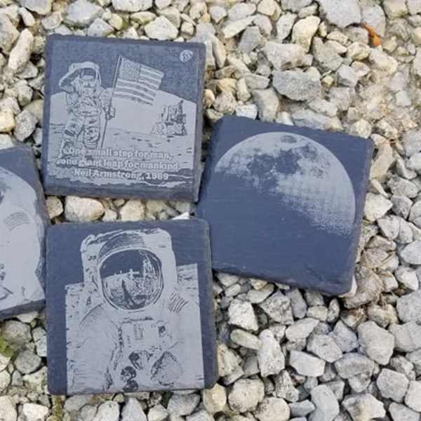 Four square slate tiles with astronaut and moon designs on gravel
