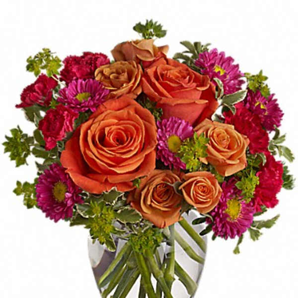 Orange roses and magenta daisies in a clear glass vase