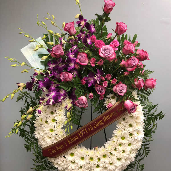 Standing floral wreath with pink roses, purple orchids, and white daisies