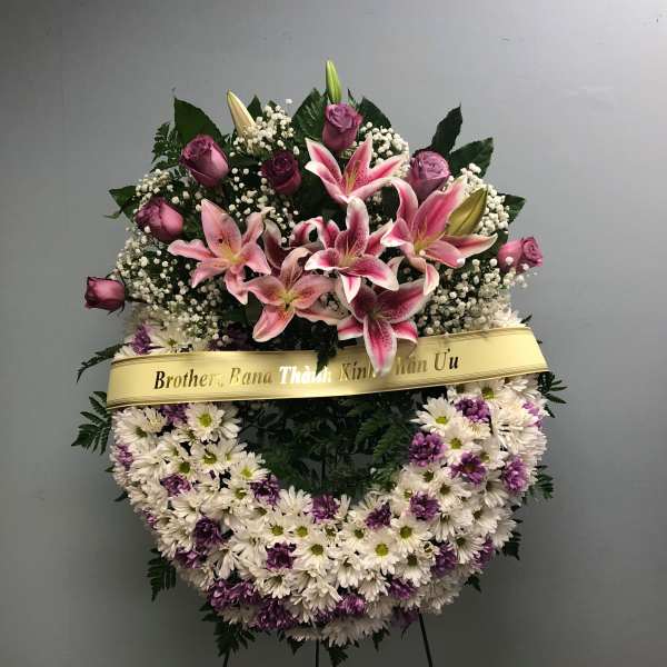 Standing floral wreath with pink lilies, roses, and white-purple daisies