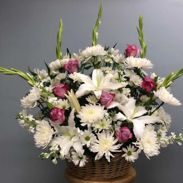 Basket arrangement of white lilies, daisies, and pink roses