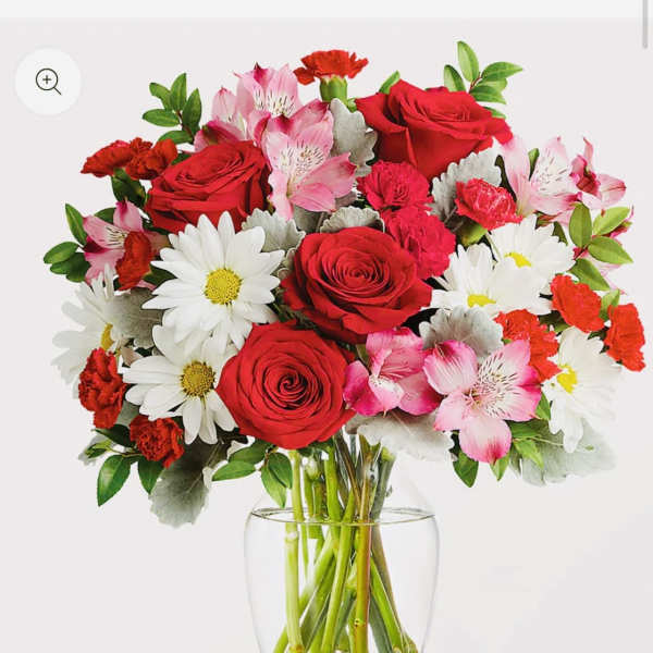 Bouquet of red roses, pink alstroemeria, and white daisies in a clear glass vase