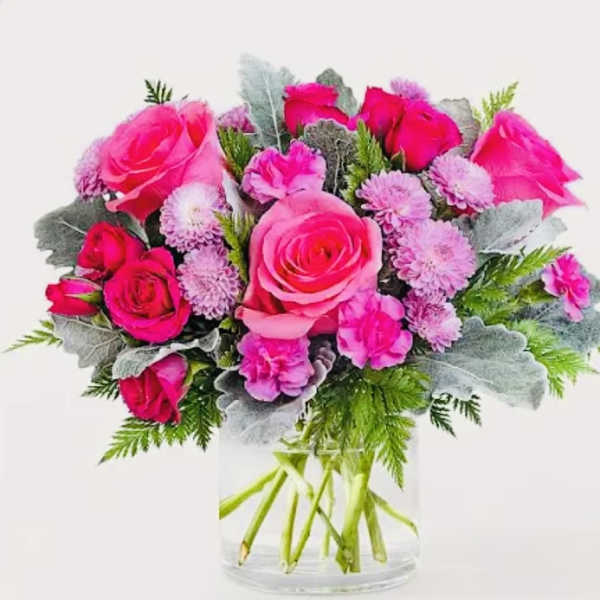 Pink roses and lavender pom-pom flowers in a clear glass vase
