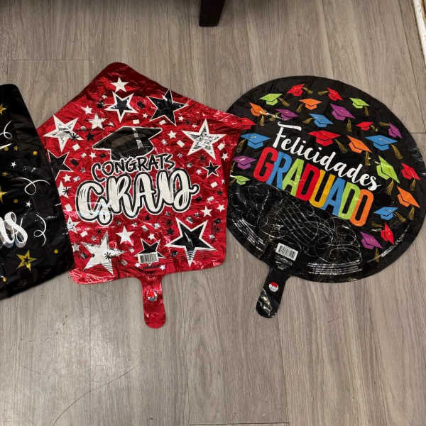 Three graduation balloons with celebratory text on the floor