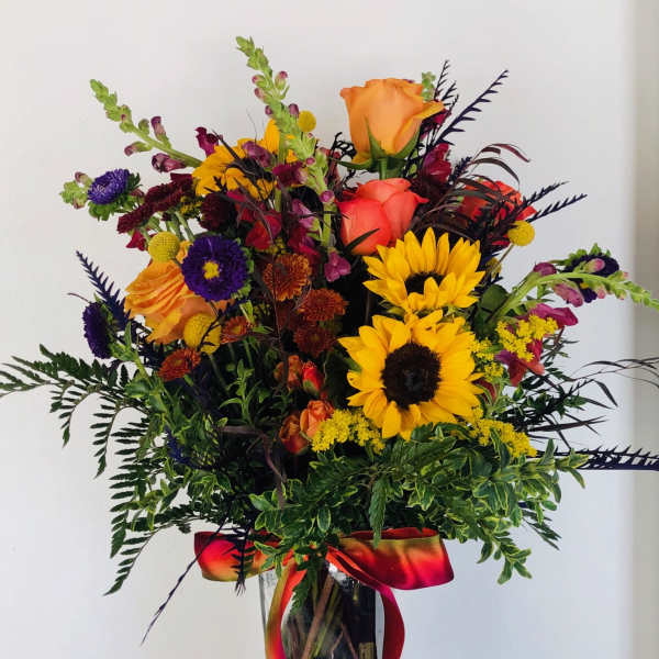 Colorful bouquet with sunflowers, roses, and a glass vase