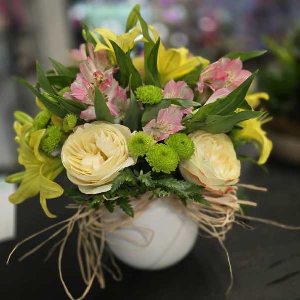 Bouquet of cream, pink, and yellow flowers in a white vase