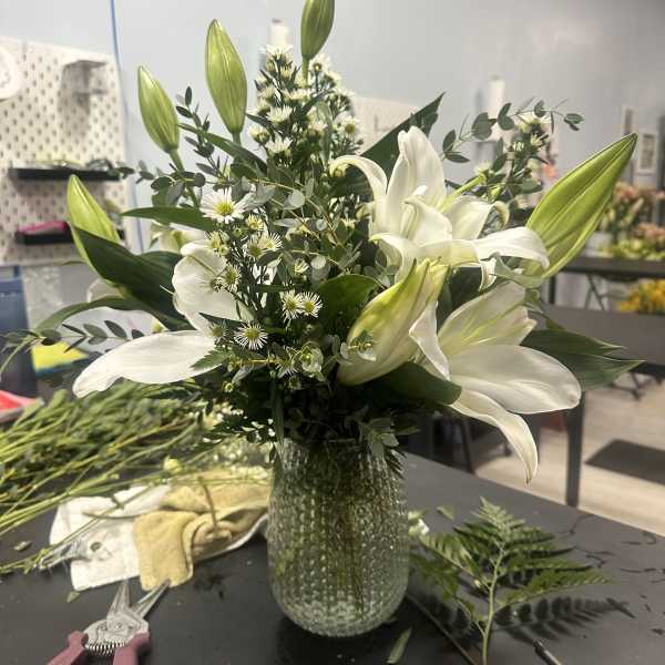 White lilies and small white daisies in a glass vase
