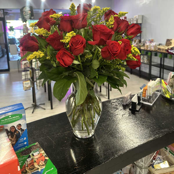 Bouquet of red roses and yellow filler flowers in a clear glass vase
