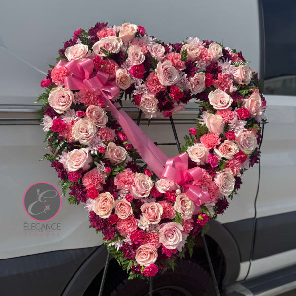 Heart-shaped floral wreath of pink roses and carnations with a ribbon bow