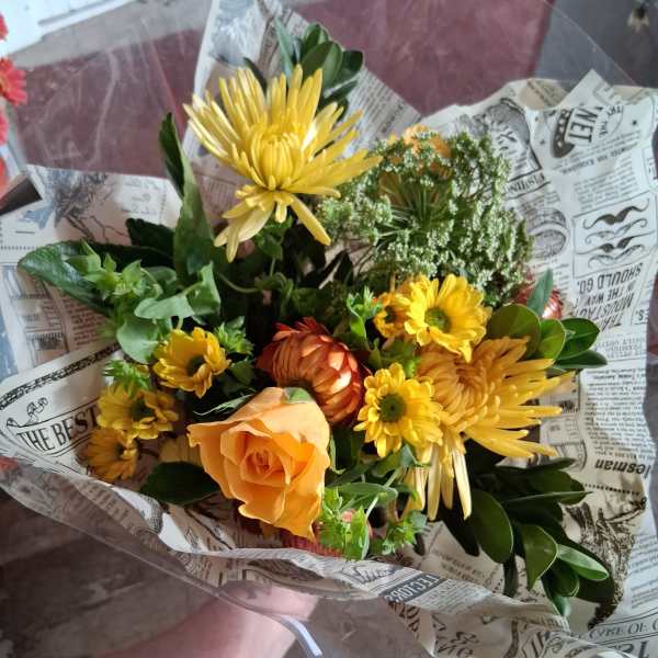 Bouquet of yellow and orange flowers wrapped in printed paper