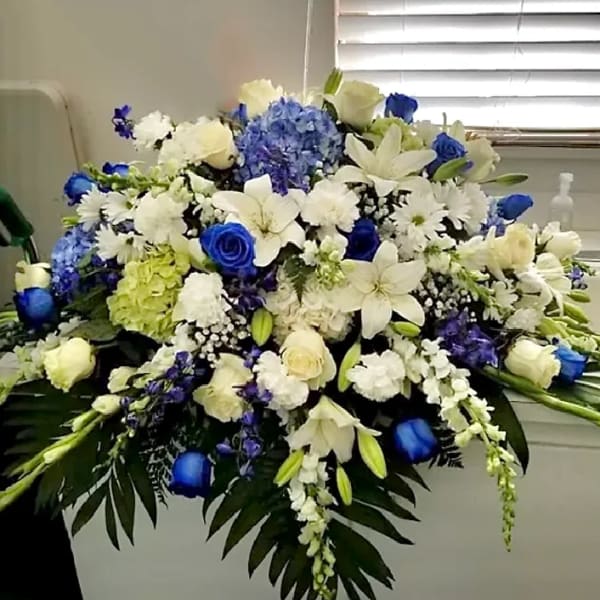 Large blue and white floral arrangement with lilies, roses, and hydrangeas