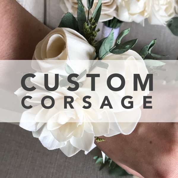 White floral corsage with roses and greenery on a wrist