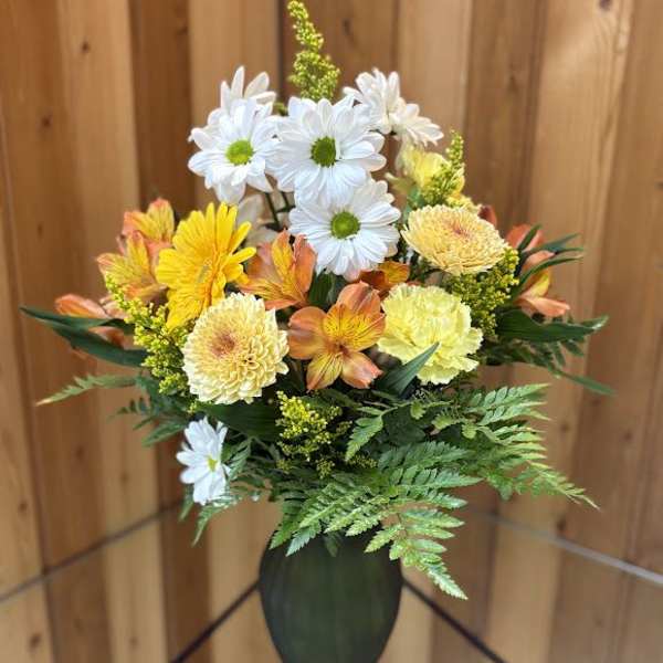 Bouquet of white daisies and yellow-orange flowers in a dark vase