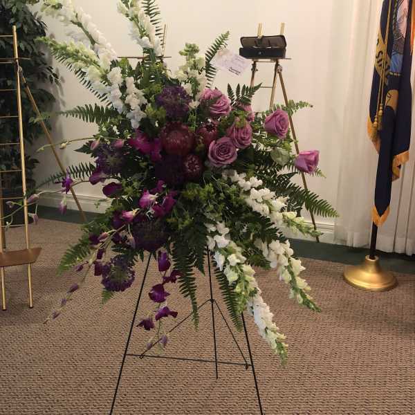 Large standing floral spray with purple and white flowers on an easel