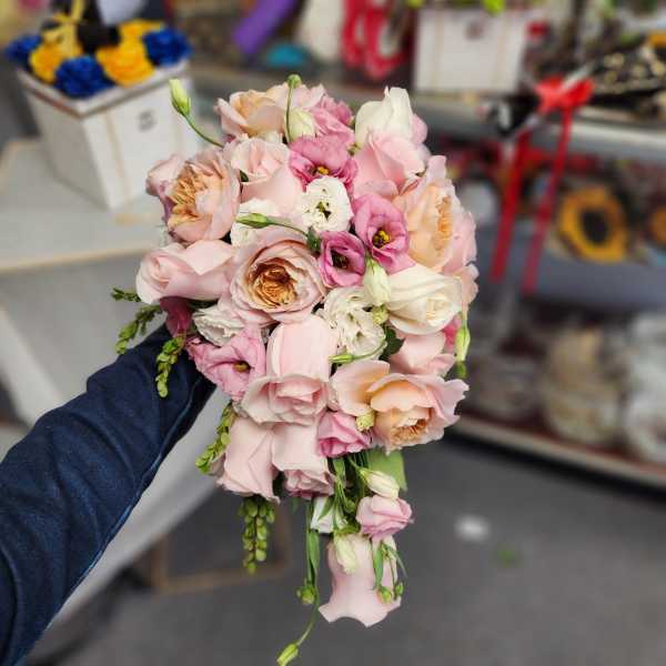 Handheld bouquet of pale pink and white roses with small pink blooms