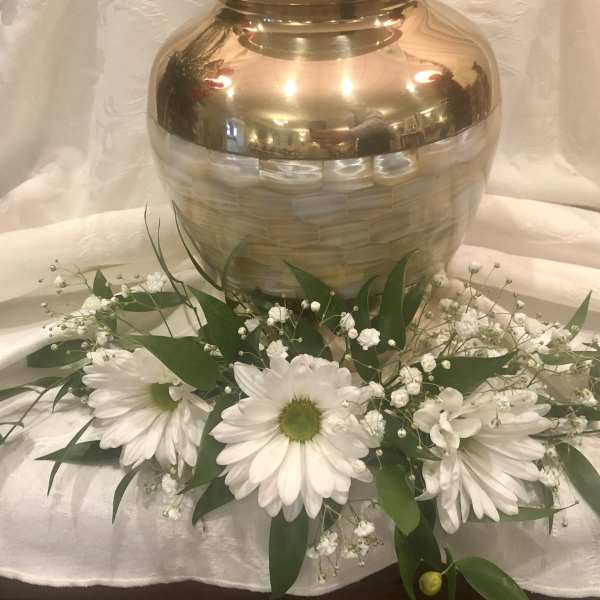 White daisy arrangement with baby's breath around a gold urn