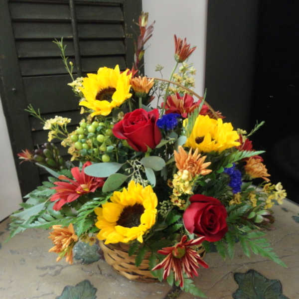 Basket arrangement with sunflowers, red roses, and mixed flowers
