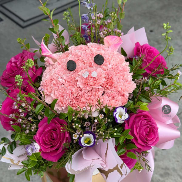 Pink floral bouquet arranged like a pig face with roses and carnations