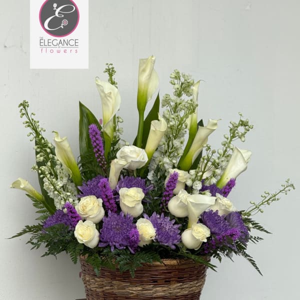 Basket arrangement of white calla lilies, roses, and purple flowers