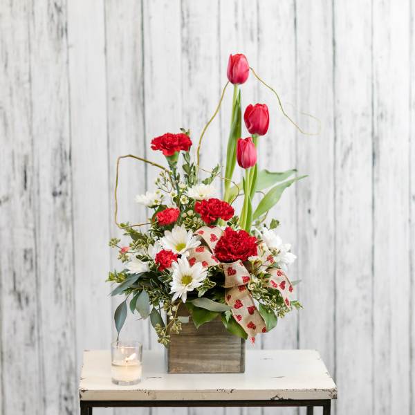 Red tulips and carnations with white daisies in a wooden box