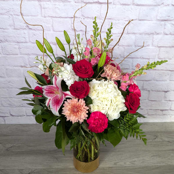 Mixed bouquet in a glass vase with red roses, lilies, hydrangea, and pink blooms