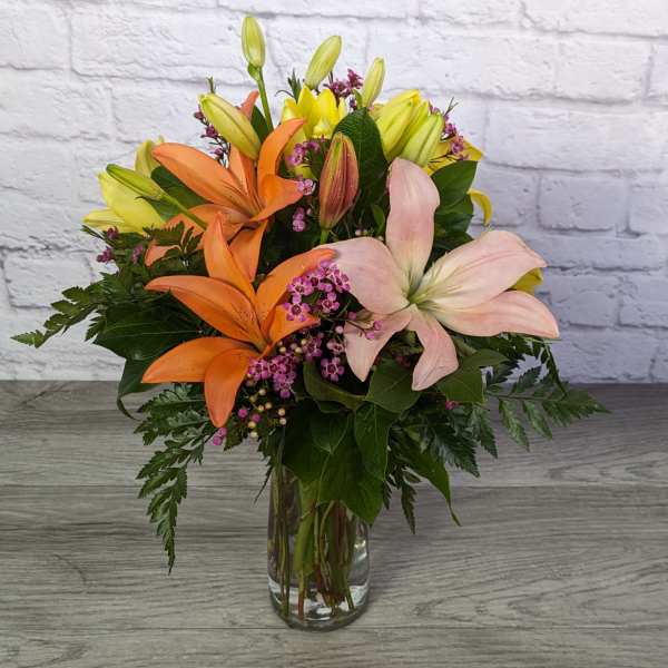 Bouquet of lilies and small purple flowers in a glass vase