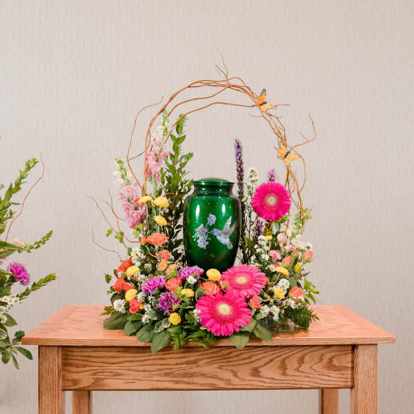 Floral arrangement with pink gerbera daisies around a green urn
