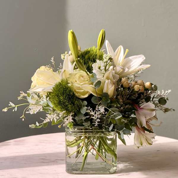 White lilies and roses in a clear glass vase
