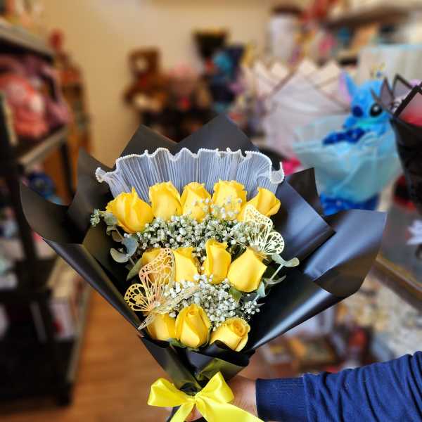 Yellow rose bouquet wrapped in black paper with a yellow ribbon