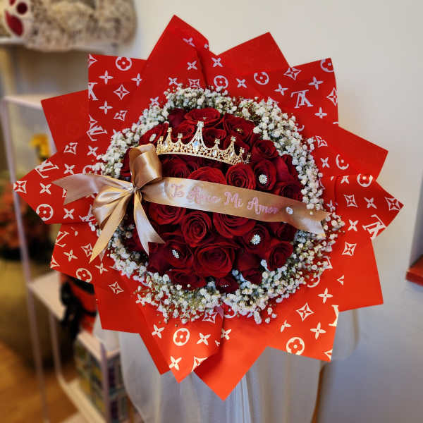 Bouquet of red roses with baby's breath, a gold ribbon, and a crown topper