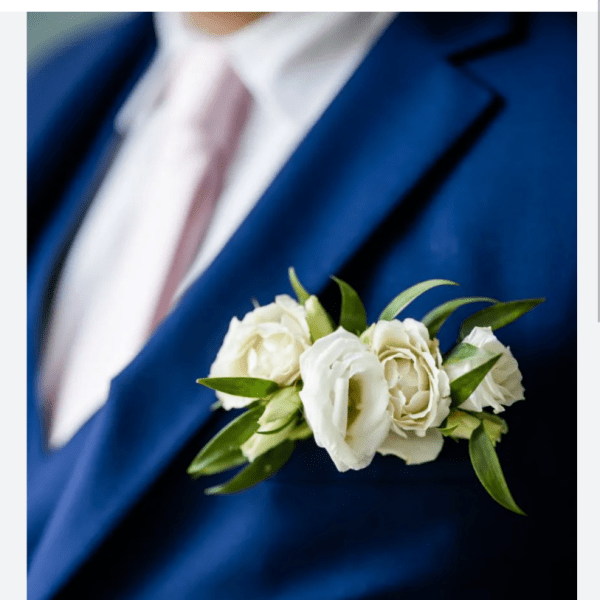 White rose boutonniere pinned to a blue suit jacket