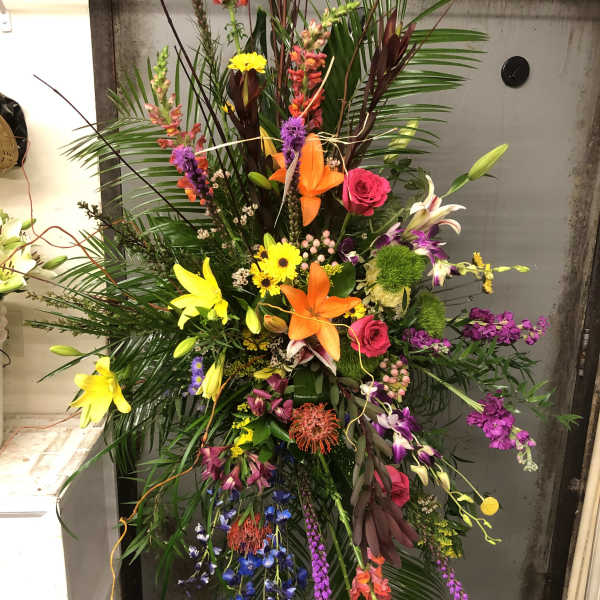 Tall tropical floral spray with lilies, roses, and orchids