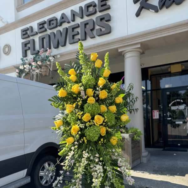 Tall standing floral spray with yellow roses and white trailing blooms
