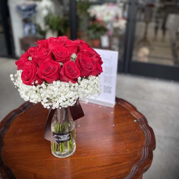 Red roses arranged in a clear glass vase with white baby's breath
