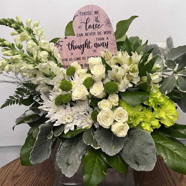 White floral arrangement with roses, lilies, and green accents in a vase
