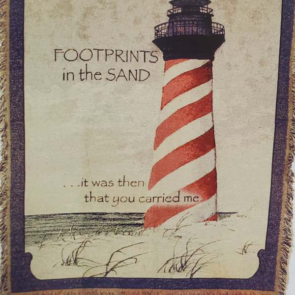 Decorative wall hanging with a lighthouse and the words "Footprints in the Sand"
