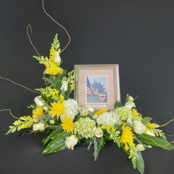 Yellow and white floral tribute with a framed photo centerpiece