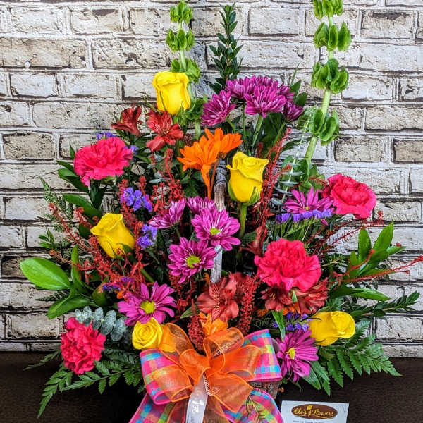 Colorful mixed flower arrangement with roses, carnations, and daisies in a basket