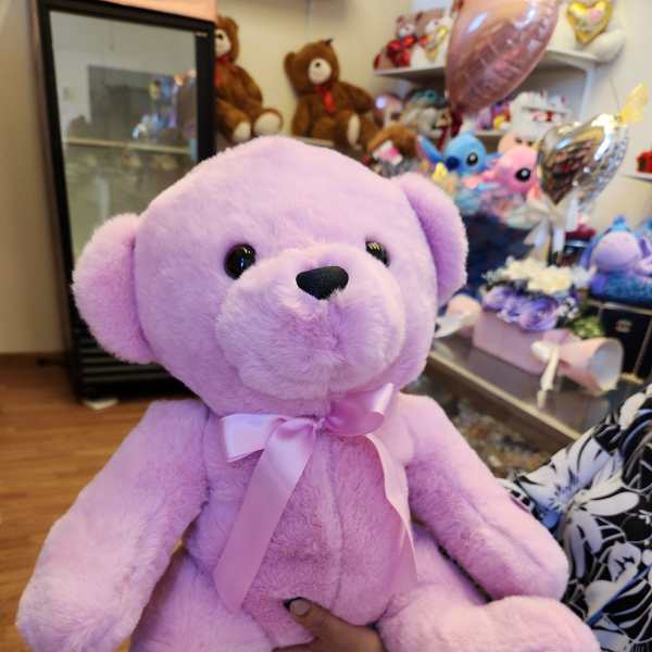 Lavender plush teddy bear with a pink ribbon bow