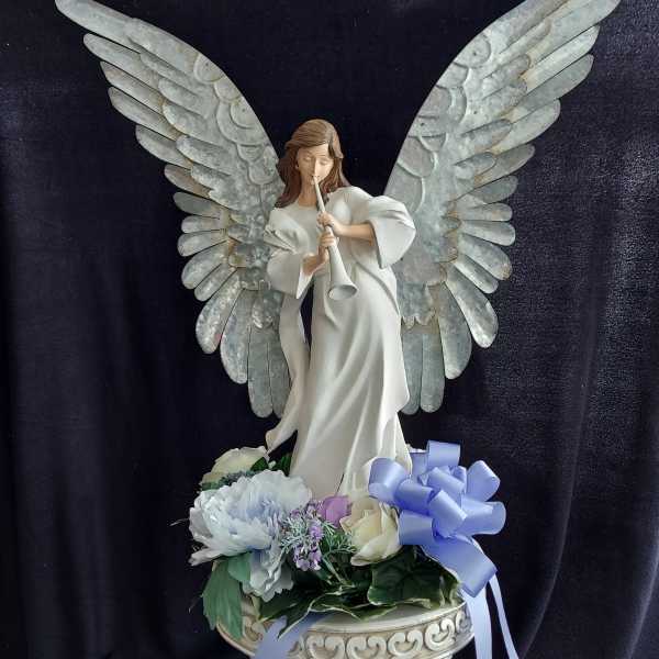 Angel figurine with wings above pastel flowers in a decorative bowl